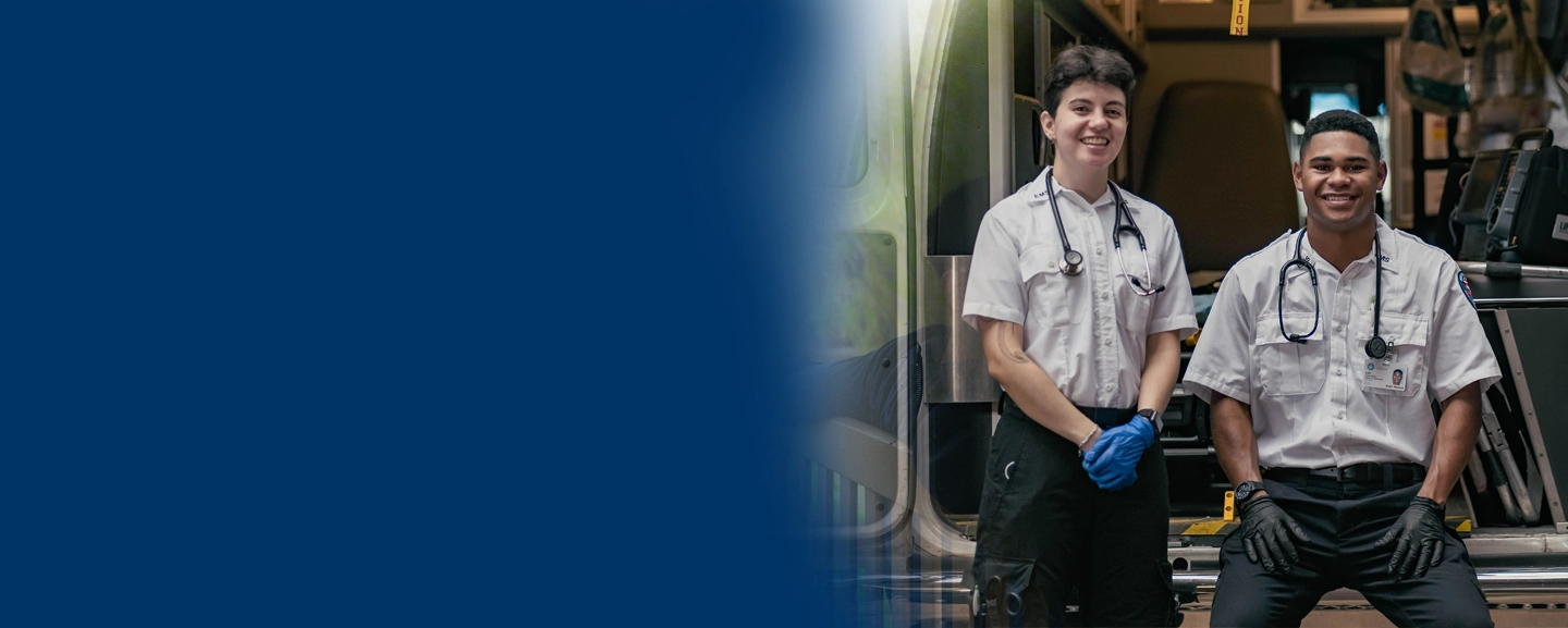 2 male EMT students in front of an ambulance back doors